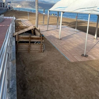 Desmonta el pasillo para personas con movilidad reducida y utiliza las maderas para hacerse una caseta para acampar en la playa de Las Canteras